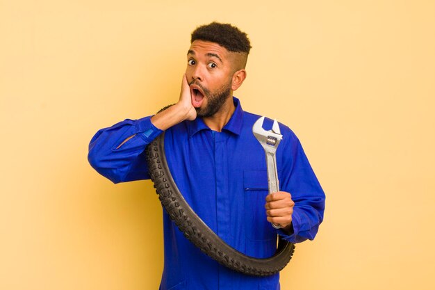 Afro cool man feeling shocked and scared bike repairman concept