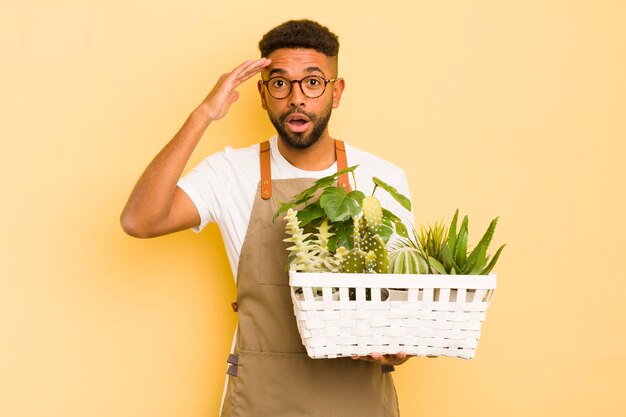 幸せそうに見えるアフロクールな男は、庭師と植物のコンセプトに驚いて驚いた