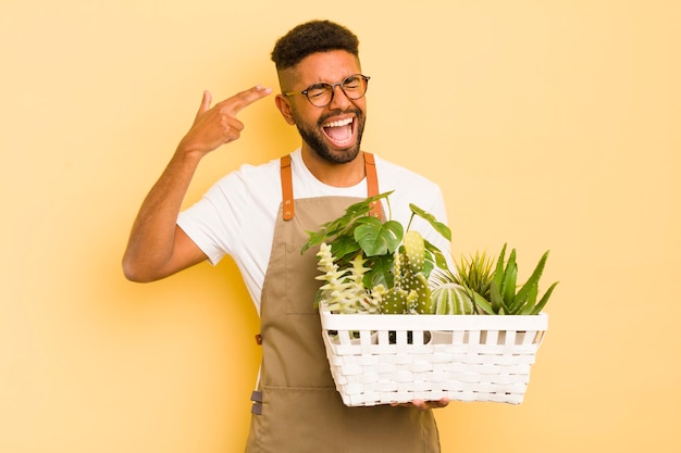 Afro cool man looking unhappy and stressed suicide gesture making gun sign gardener and plant concept