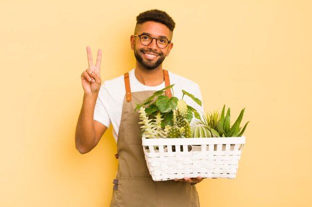 Afro cool man smiling and looking friendly showing number two gardener and plant concept