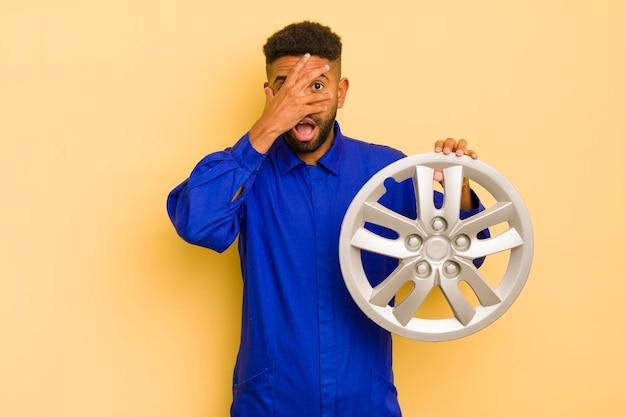 Foto afro-coole man die geschokt, bang of doodsbang zijn gezicht bedekt met het concept van de handfietsreparateur