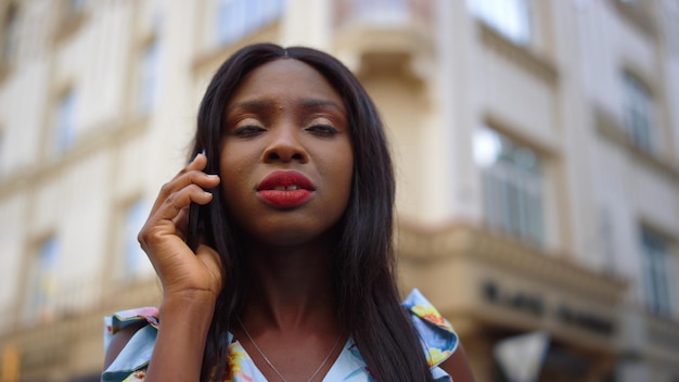 Afro girl having phone conversation on street Lady talking smartphone in city