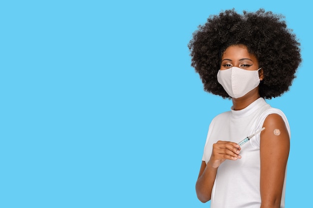 Afro girl shows the vaccine mark holding the syringe showing that she has been vaccinated covid19