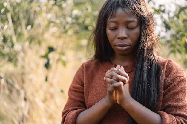 Afro Girl with closed eyes, praying outdoors