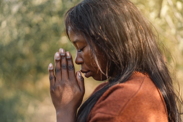 Afro Girl with closed eyes, praying outdoors