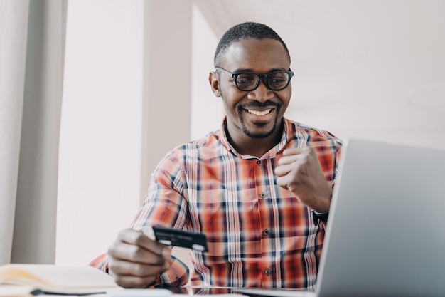 Афро парень получает прибыль Мужчина покупает или заказывает онлайн концепцию электронной коммерции и потребительства