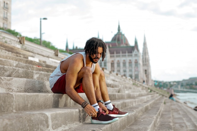 Foto ragazzo afro legando le scarpe