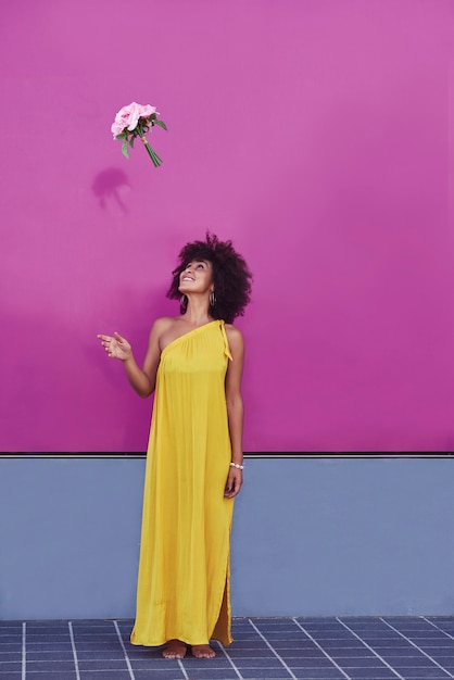 Afro-haired mulatto woman in a yellow dress and purple background.