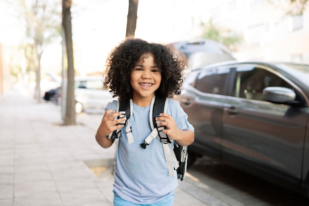 Bel ragazzo afro, con lo zaino, esce dalla macchina per andare a scuola, torna a scuola, scuola materna