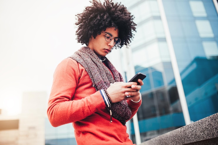 Foto afro jonge man met een mobiele telefoon terwijl hij in de stad staat