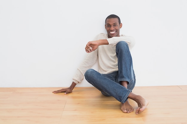 Afro jonge man zittend op de vloer in een lege ruimte