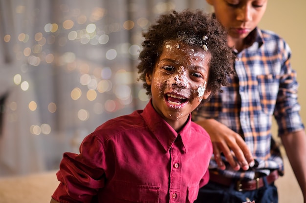 La faccia spalmata di torta di un bambino afro.