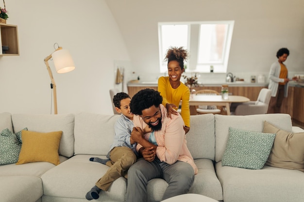 Afro-kinderen vermaken zich met hun vader in de knusse woonkamer