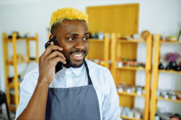 Afro male potter talking on the phone in his studio