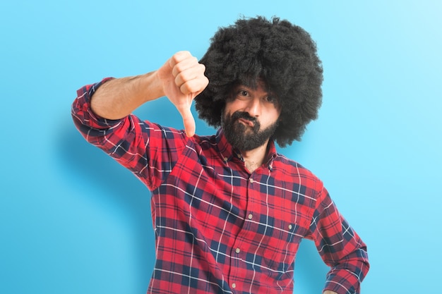 Afro uomo che fa cattivo segnale su sfondo colorato