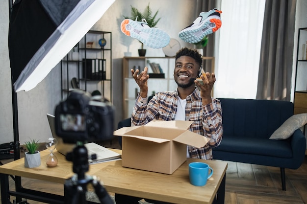 Афро-мужчина распаковывает кроссовки для создания видеоконтента