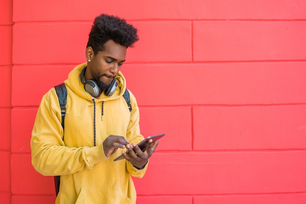 Afro man using his digital tablet with earphones