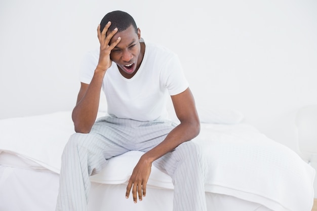 Афро-мужчина, зевая в постели у себя дома