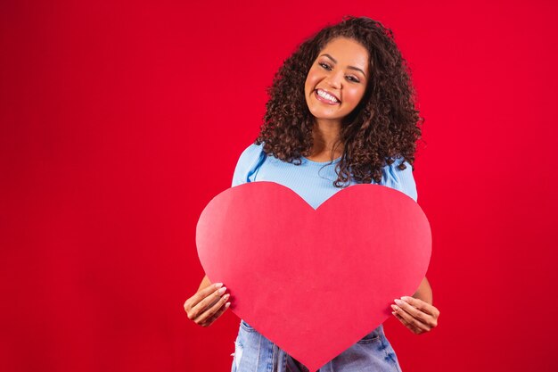 Afro meisje bedrijf in handen hart vorm amour geïsoleerd over rode achtergrond