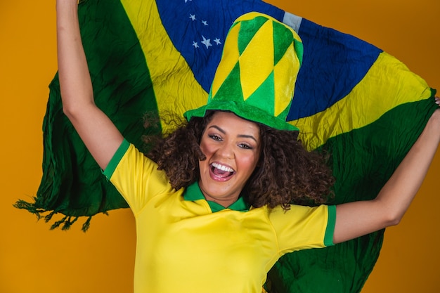 Afro meisje juichen voor favoriete Braziliaanse team, met nationale vlag op gele achtergrond.