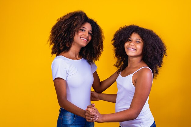 Afro moeder en dochter dansen op gele achtergrond