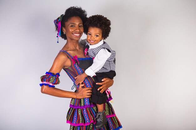 Afro-moeder en zoon gekleed voor juni-feest Braziliaans feest genaamd Festa Junina ter ere van Sao Joao Hand in haar glimlachend en armen openend