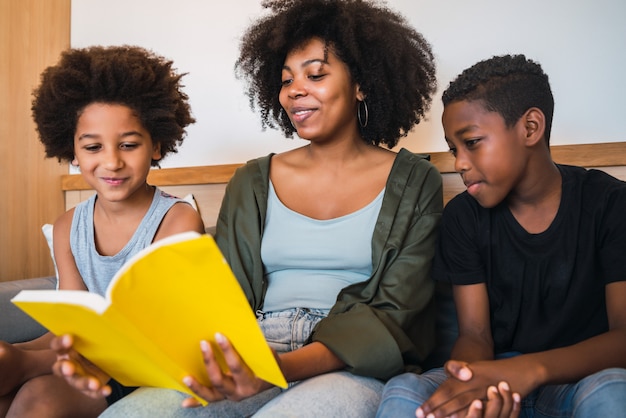 Afro mother reading a book to her children.