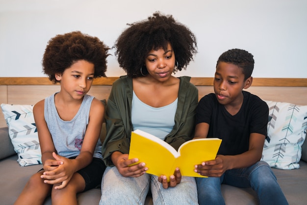 Afro mother reading a book to her children.