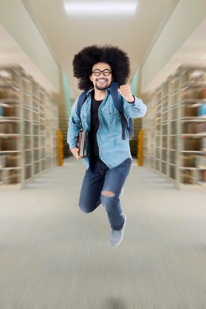 Afro student jumping in the library