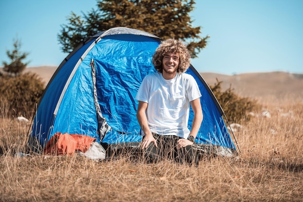 An afro teenager comes out of a mountain tent after a sleepless night. High quality photo