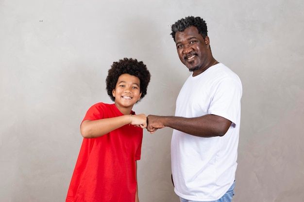 Afro vader en zoon vieren op grijze achtergrond blij voor vaderdag of kinderdag