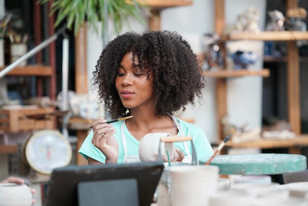 Afro-vrouw die aardewerk maakt in werkplaats Vormgeven van natte klei op aardewerkwiel