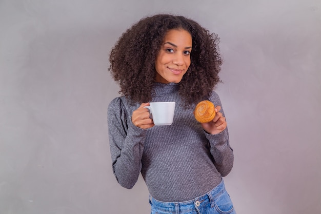 Afro-vrouw die donuts eet en koffie drinkt