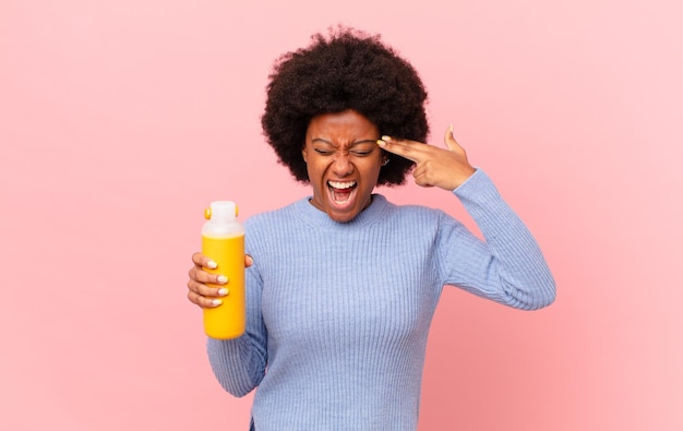 Afro-vrouw die er ongelukkig en gestrest uitziet, zelfmoordgebaar maakt een pistoolteken met de hand, wijzend naar het hoofd smoothy concept