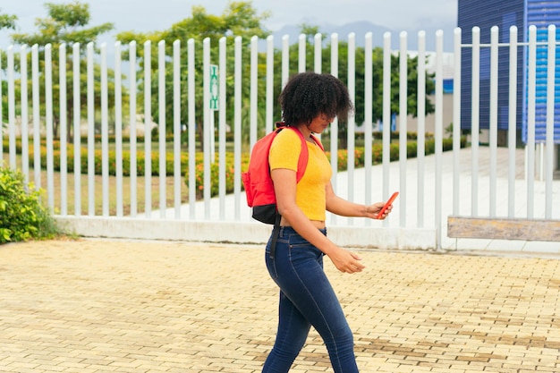 Afro-vrouw die loopt en een sms leest op haar mobiele telefoon