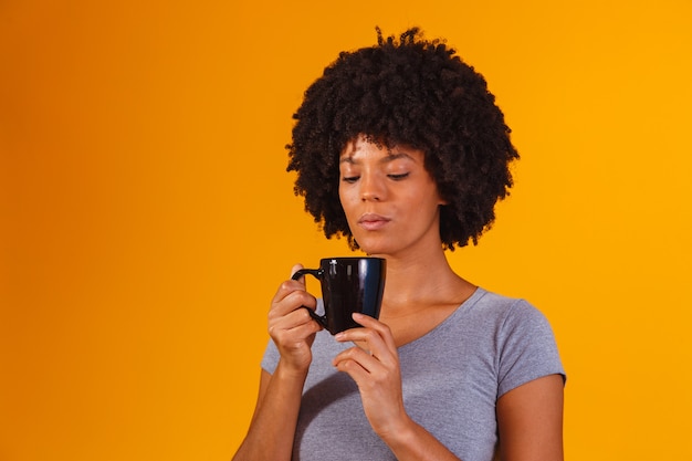 Afro-vrouw die thee drinkt op geel