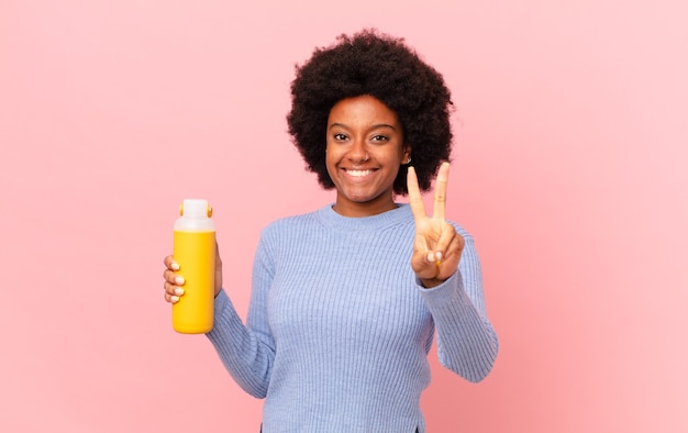 Afro-vrouw lacht en ziet er gelukkig, zorgeloos en positief uit, gebarend overwinning of vrede met één hand. smoothy concept