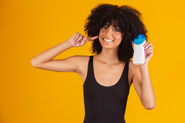 Afro-vrouw met een zonnebrandcrème in haar hand met vrije ruimte voor tekst