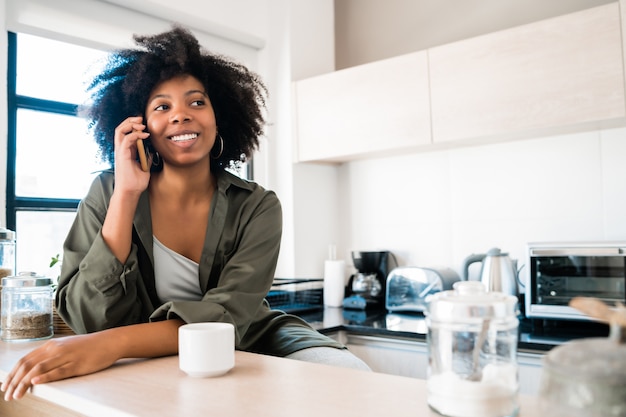 Afro vrouw praten aan de telefoon thuis.