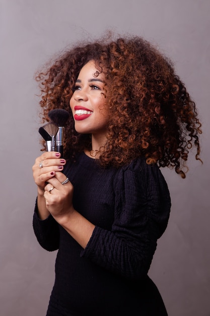 Afro vrouw professionele make-up artiest met make-up kwasten.