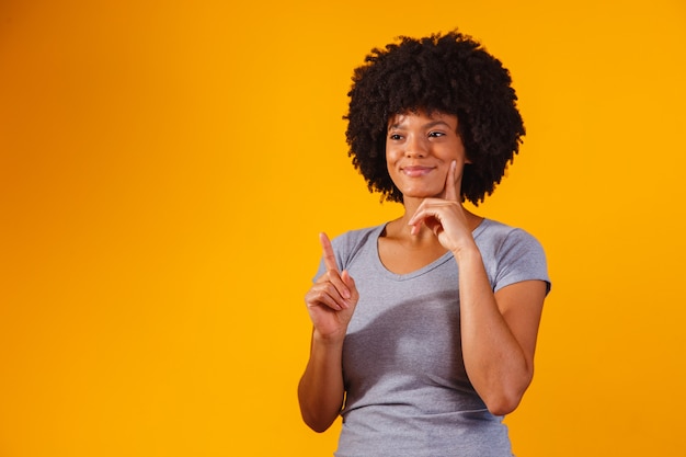 Afro-vrouw wijzend op geel met ruimte voor de tekst