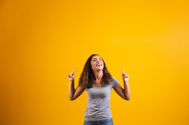 Afro-vrouw wijzend op gele achtergrond met ruimte voor de tekst