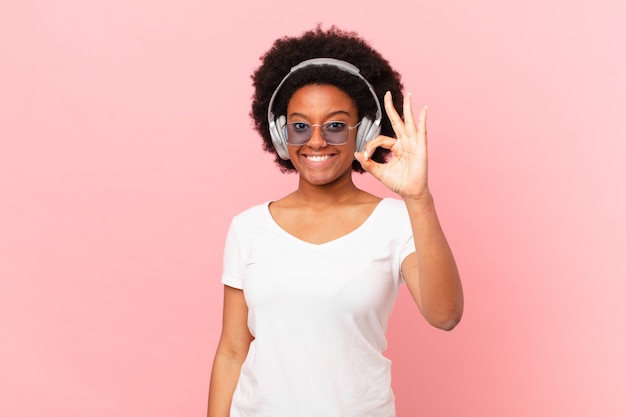 Afro woman feeling happy, relaxed and satisfied, showing approval with okay gesture, smiling. music concept