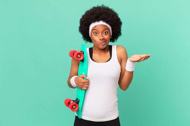 Photo afro woman feeling puzzled and confused, doubting, weighting or choosing different options with funny expression. skateboard concept