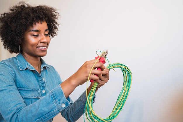 Donna afro che ripara problema di elettricità a casa.