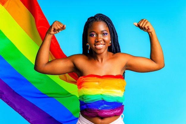 Afro woman holding LGBT pride flag in blue studio background