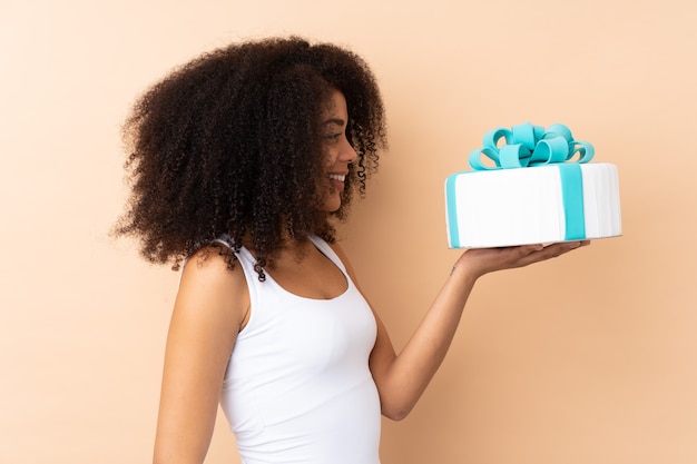 afro woman holding a white cake with blue bow