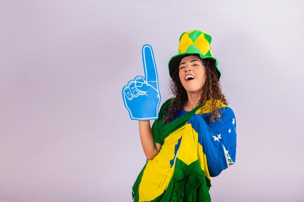 Afro woman looking at camera holding soccer glove in brazilian outfit.