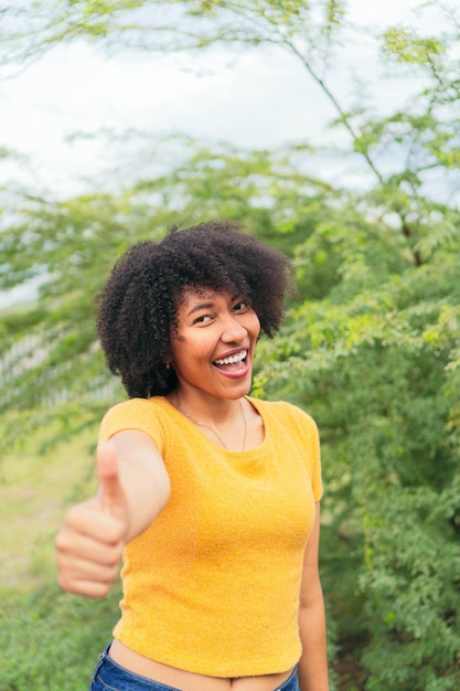 Афро женщина смотрит в камеру, позируя на естественном зеленом фоне