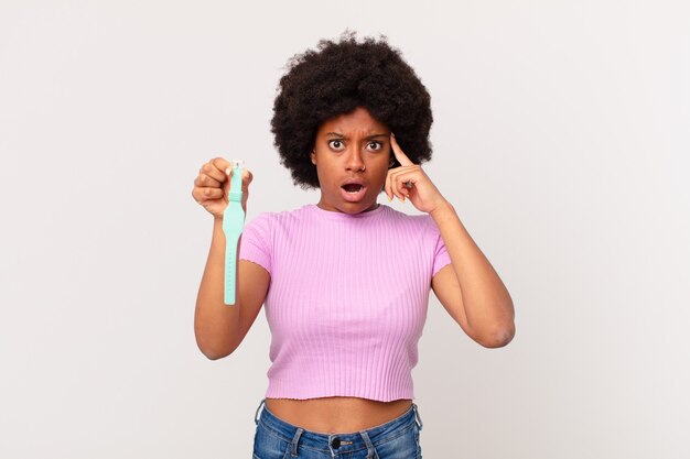 Afro woman looking surprised, open-mouthed, shocked, realizing a new thought, idea or concept watch concept